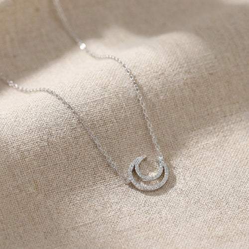 Elegant celestial moon necklace worn by female model in natural light